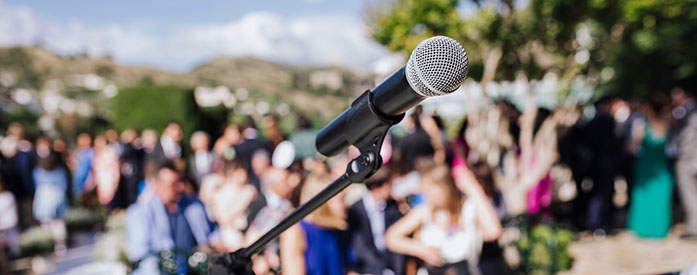 Close up view of a microphone with a blurred view of the audience in the background