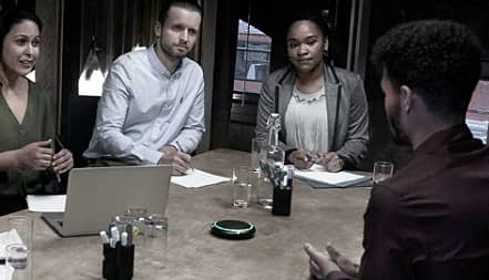 4 people sitting around a table in a small meeting room.