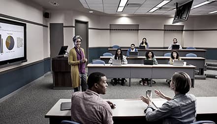 A woman makes a presentations in front of a group of eight people.